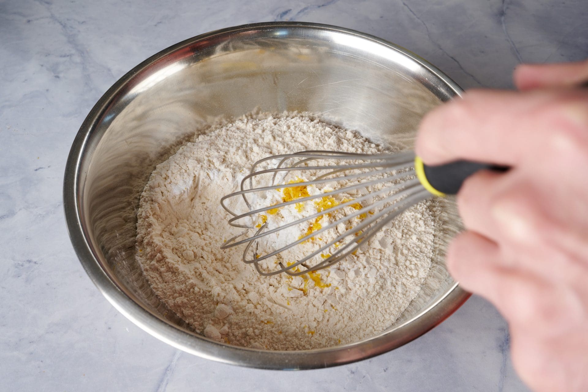Sourdough starter discard cake step by step: Whisking flour, zest, and other ingredients.